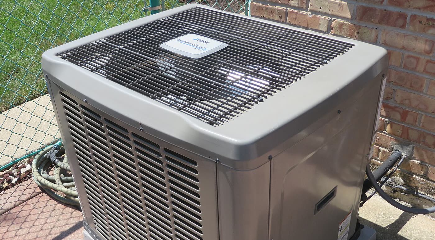 A York outdoor condenser on a pad beside a brick wall