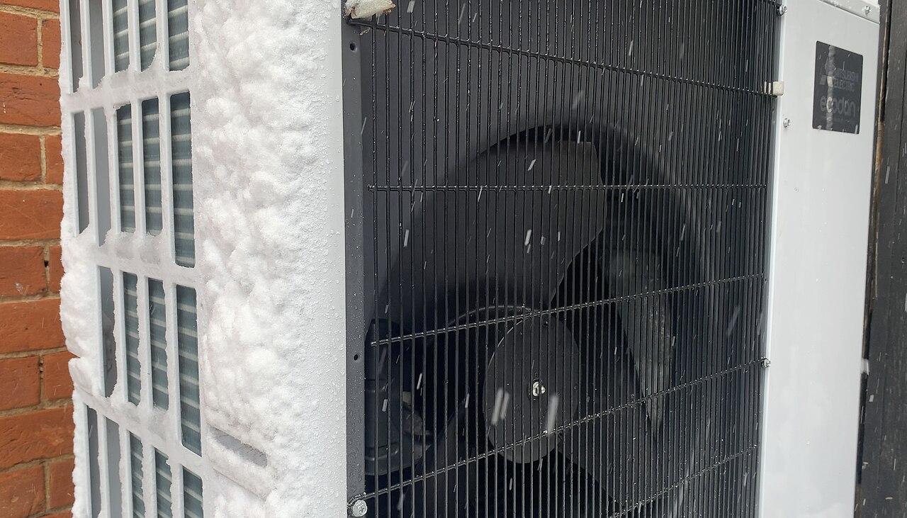 A heat pump outdoor unit beside a brick wall