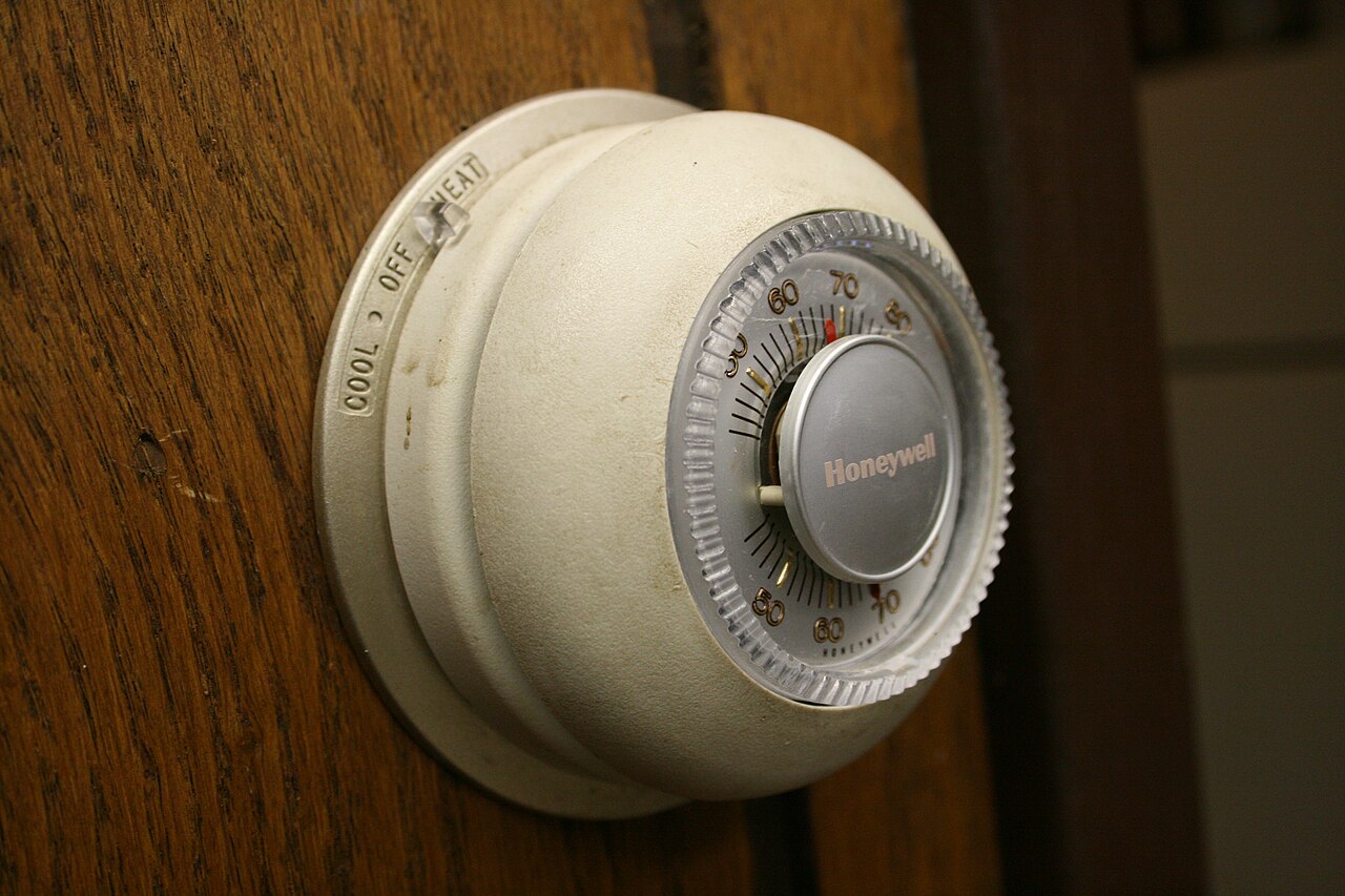 A round Honeywell thermostat on a wood wall